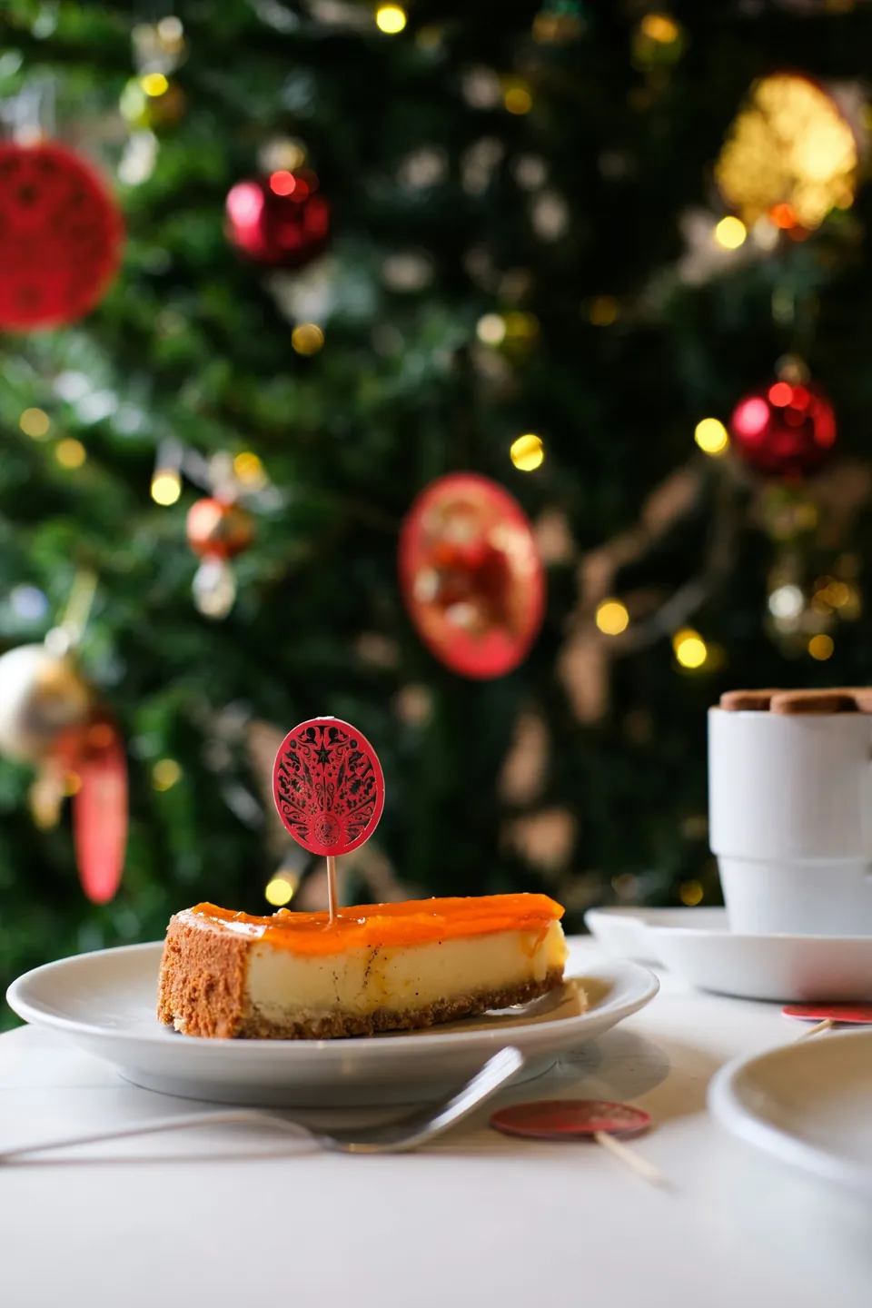 A slice of cheesecake in front of the lit tree