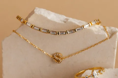 Gold bracelet set with baguette stones, on a white stone block