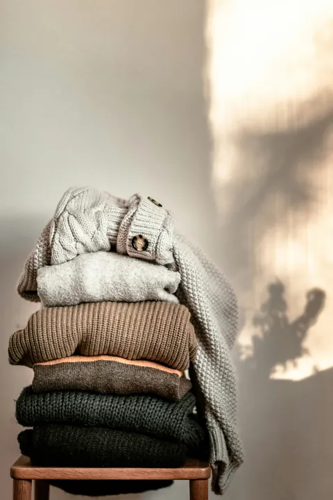 The boutique&rsquo;s photo of folded knitwear on a wooden stool